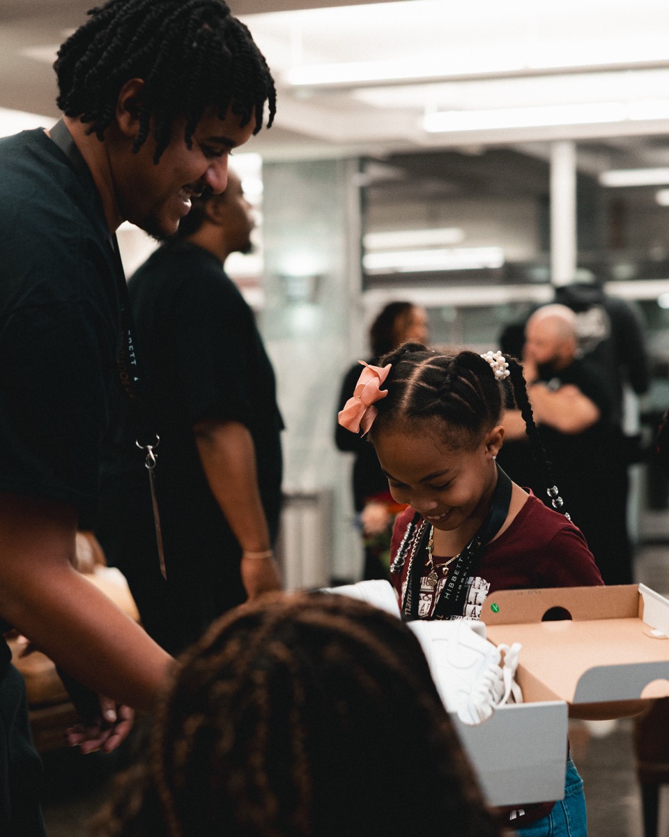 A fan lacing up custom Nike sneakers at the Hibbett x Nike lobby popup.